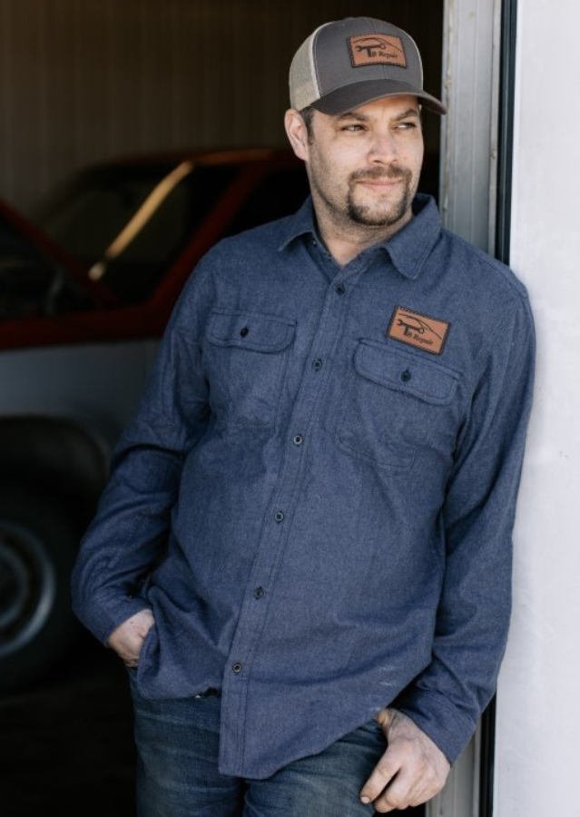 Man wearing a leather patch trucker hat and branded work shirt