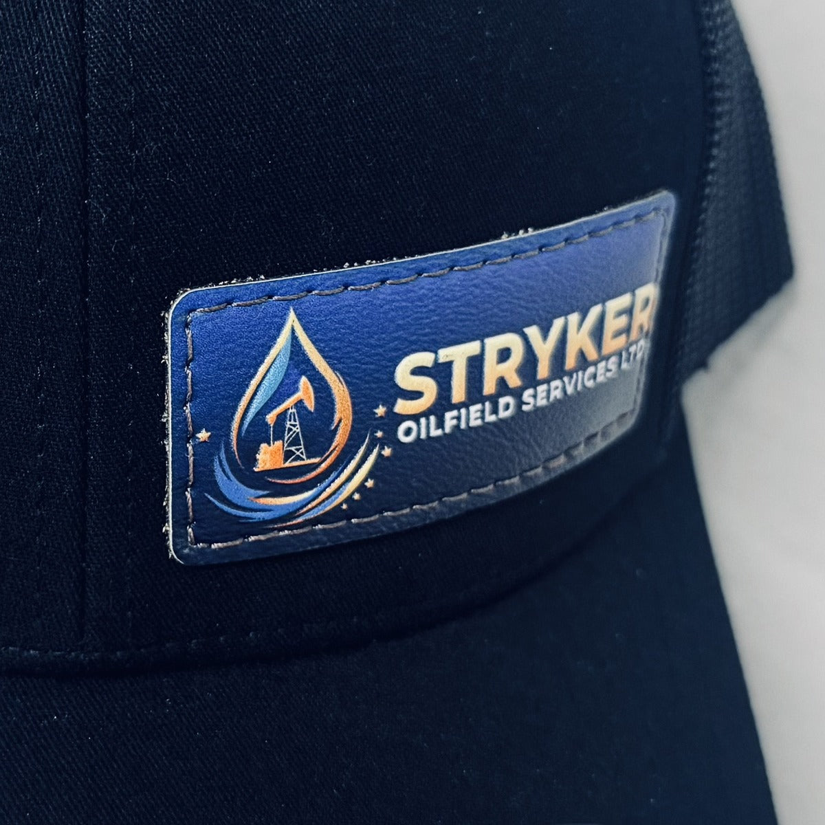 Rectangular 3D resin patch with a blue gradient background and gold oil drop logo on a navy cap