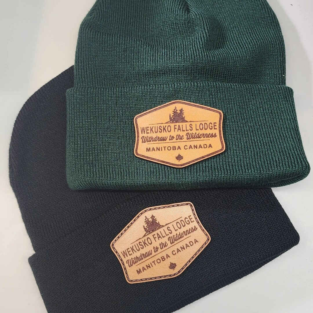 Green and navy custom toques with an engraved Wekusko Falls Lodge Manitoba leather patch